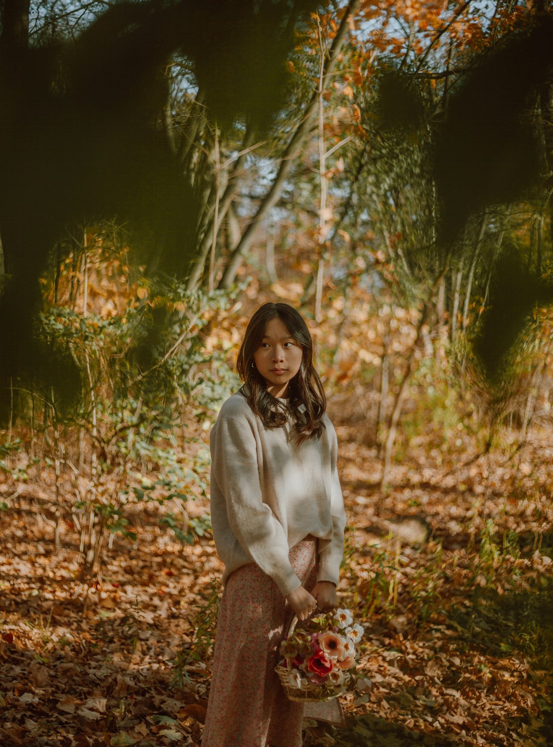 woman in white long sleeve shirt and gray pants sitting on brown dried leaves during daytime