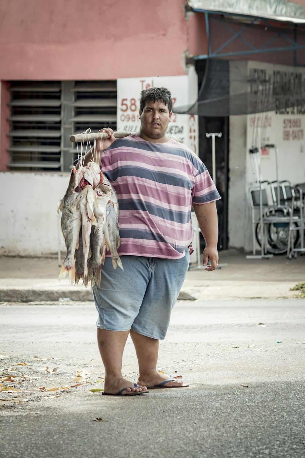 man in red and white stripe crew neck t-shirt holding fish