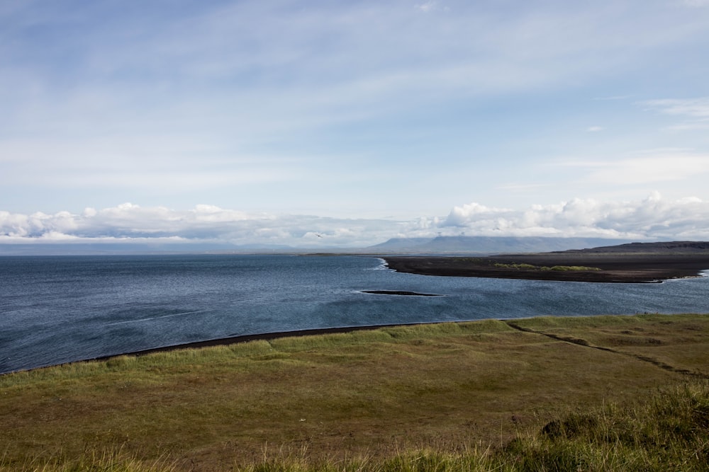 a large body of water sitting on top of a lush green hillside