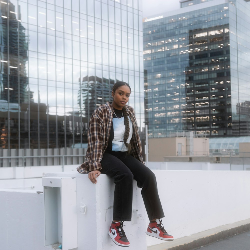 woman in black pants sitting on white concrete bench during daytime