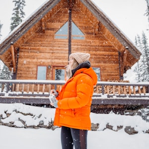 woman in orange jacket standing on snow covered ground
