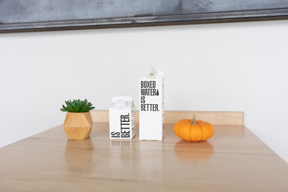 white and black labeled carton beside orange pumpkin on brown wooden table