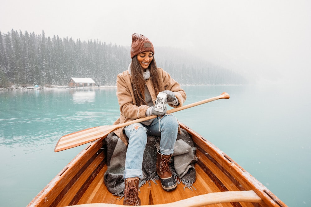 man in brown jacket and blue denim jeans sitting on brown wooden boat during daytime