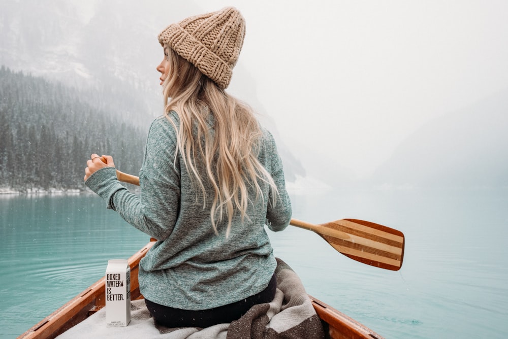 woman in gray long sleeve shirt sitting on brown wooden chair