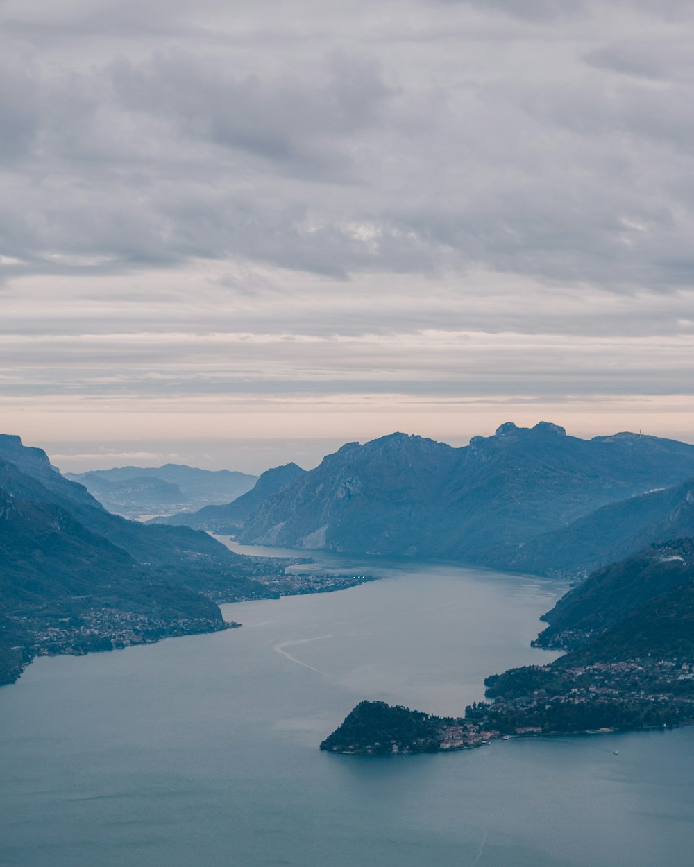 body of water between mountains under white clouds during daytime