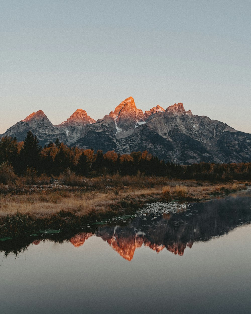 the mountains are reflected in the still water of the river