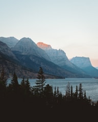 A panoramic view of the Nebrodi mountains with dense forests and a serene lake at sunset.