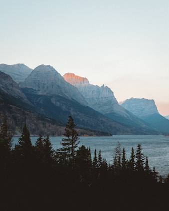 A panoramic view of the Nebrodi mountains with dense forests and a serene lake at sunset.