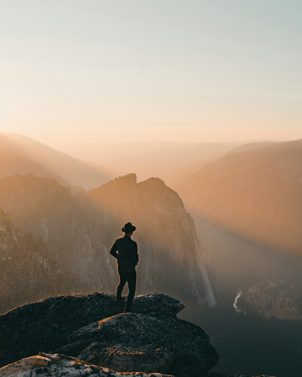 silhouette of person standing on rock formation during daytime