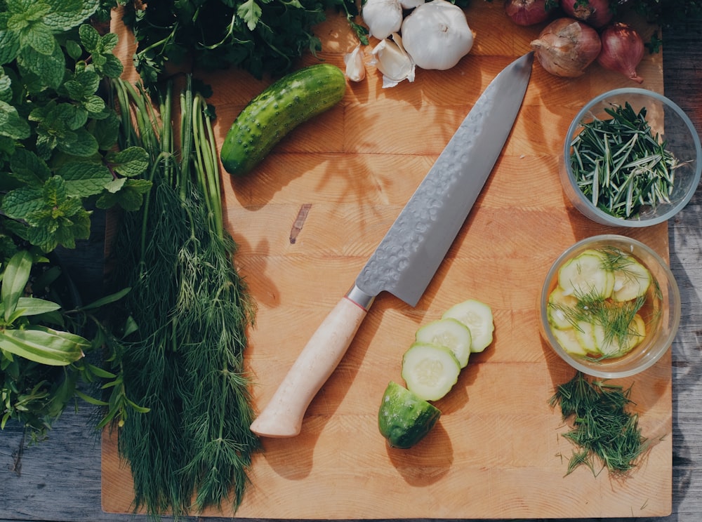 geschnittene Gurke und grünes Gemüse auf braunem Holztisch