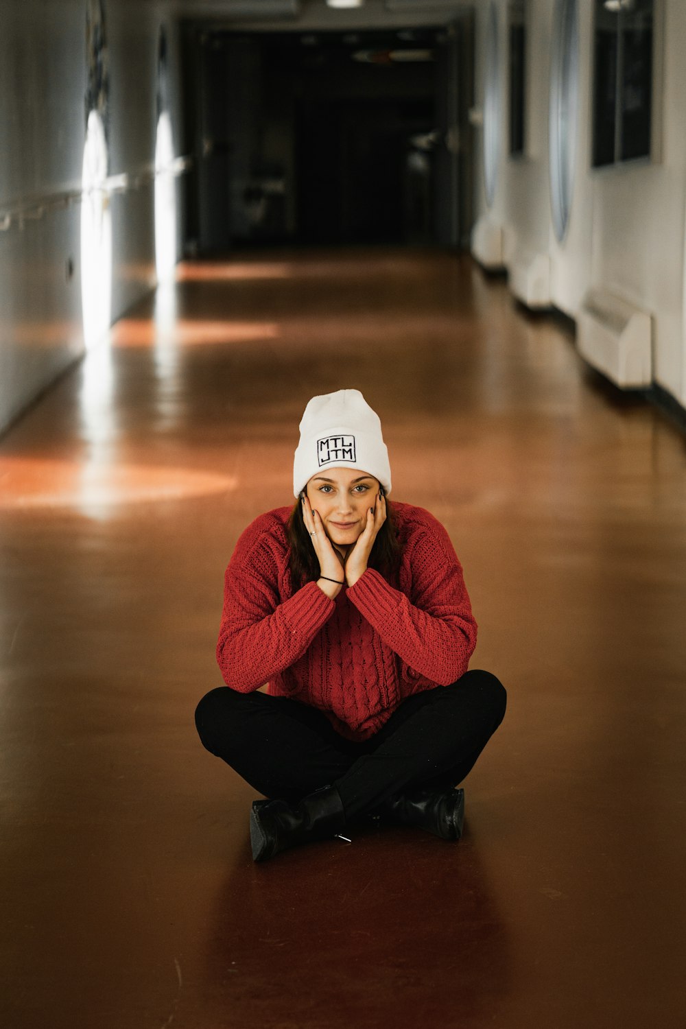 woman in red sweater and black pants sitting on floor