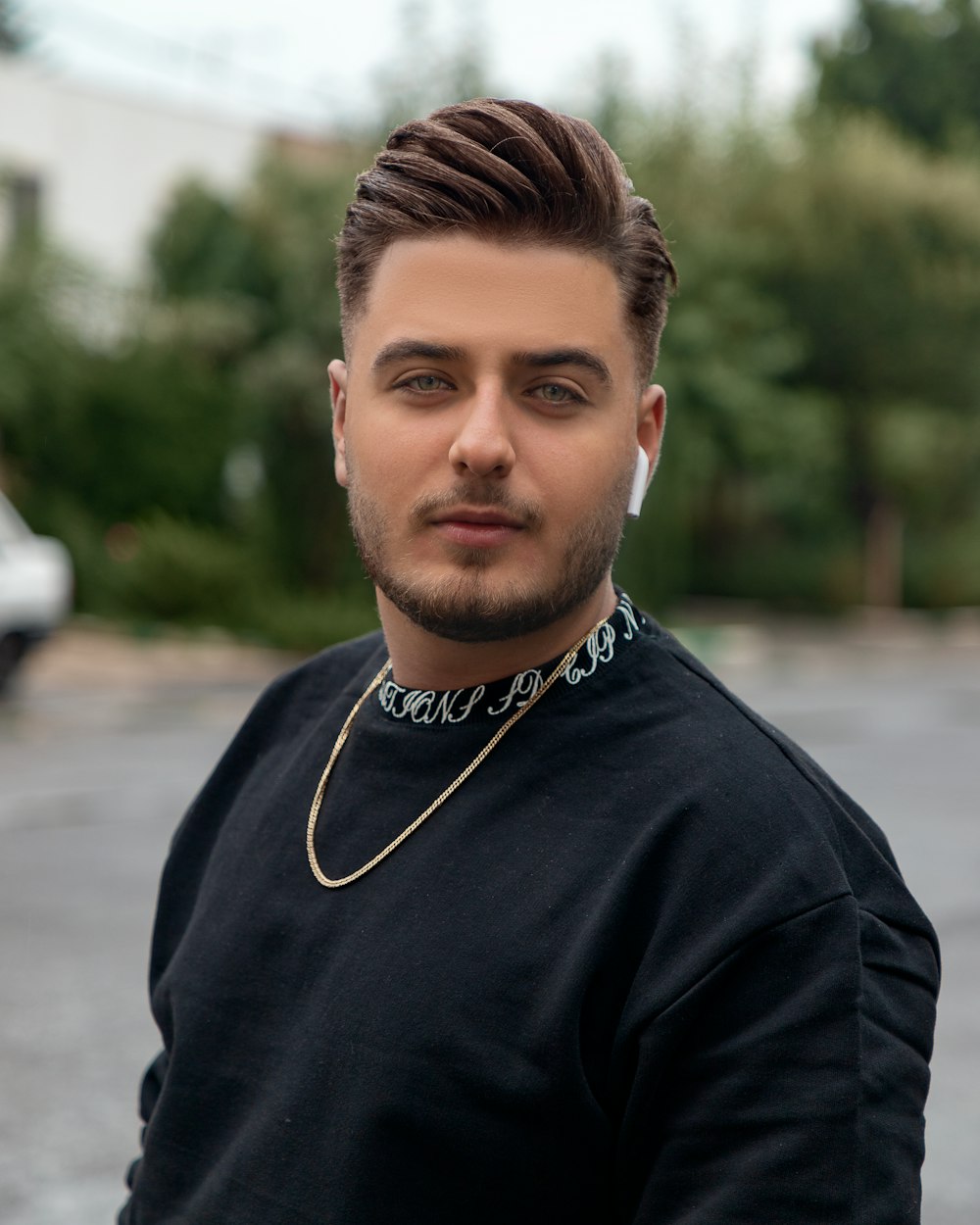 man in black crew neck shirt wearing gold necklace