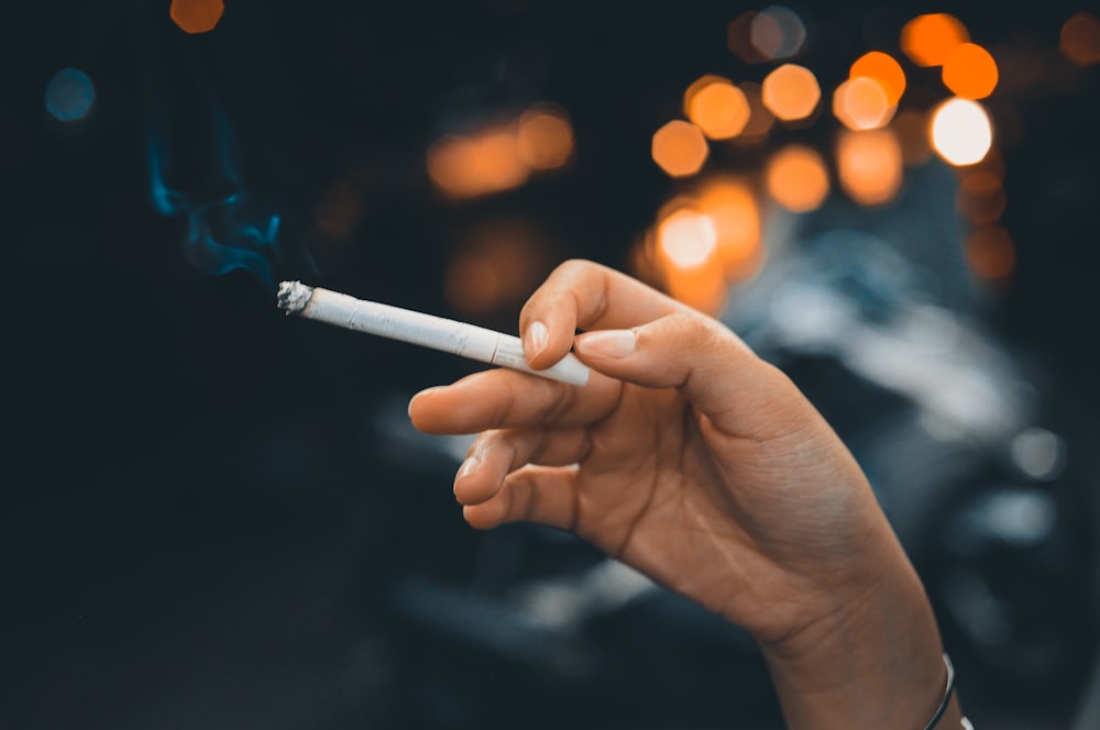 person holding white cigarette stick