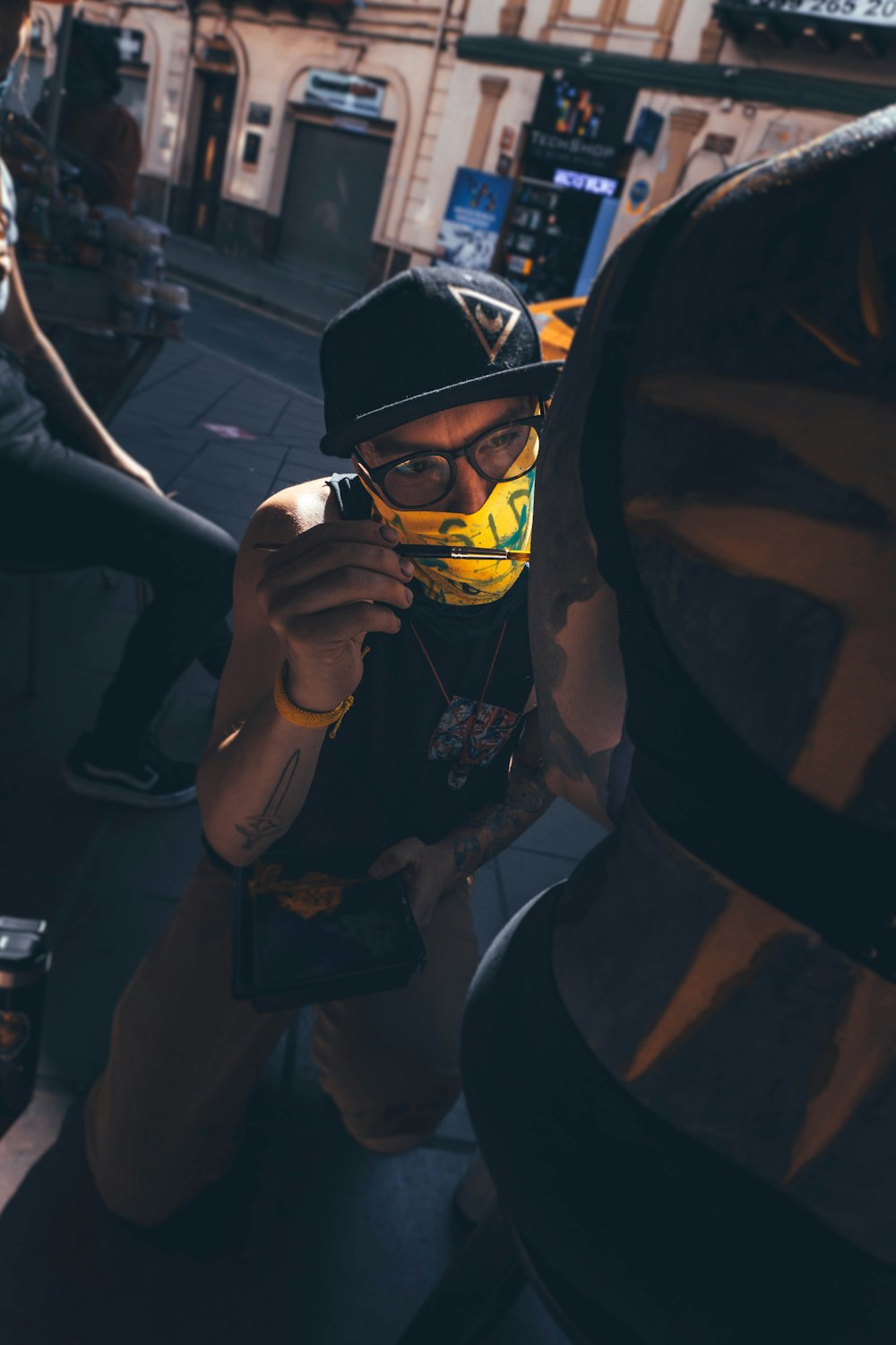 man in black jacket wearing black sunglasses holding yellow smartphone