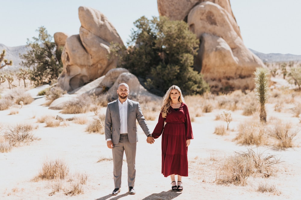 man and woman standing on white sand during daytime