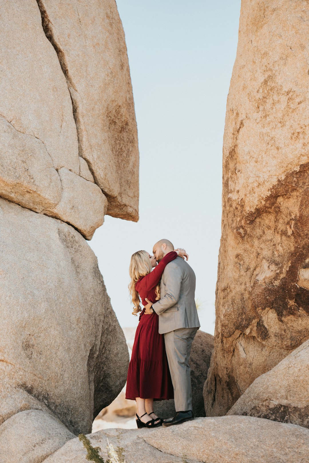 couple standing beside brown rock formation during daytime