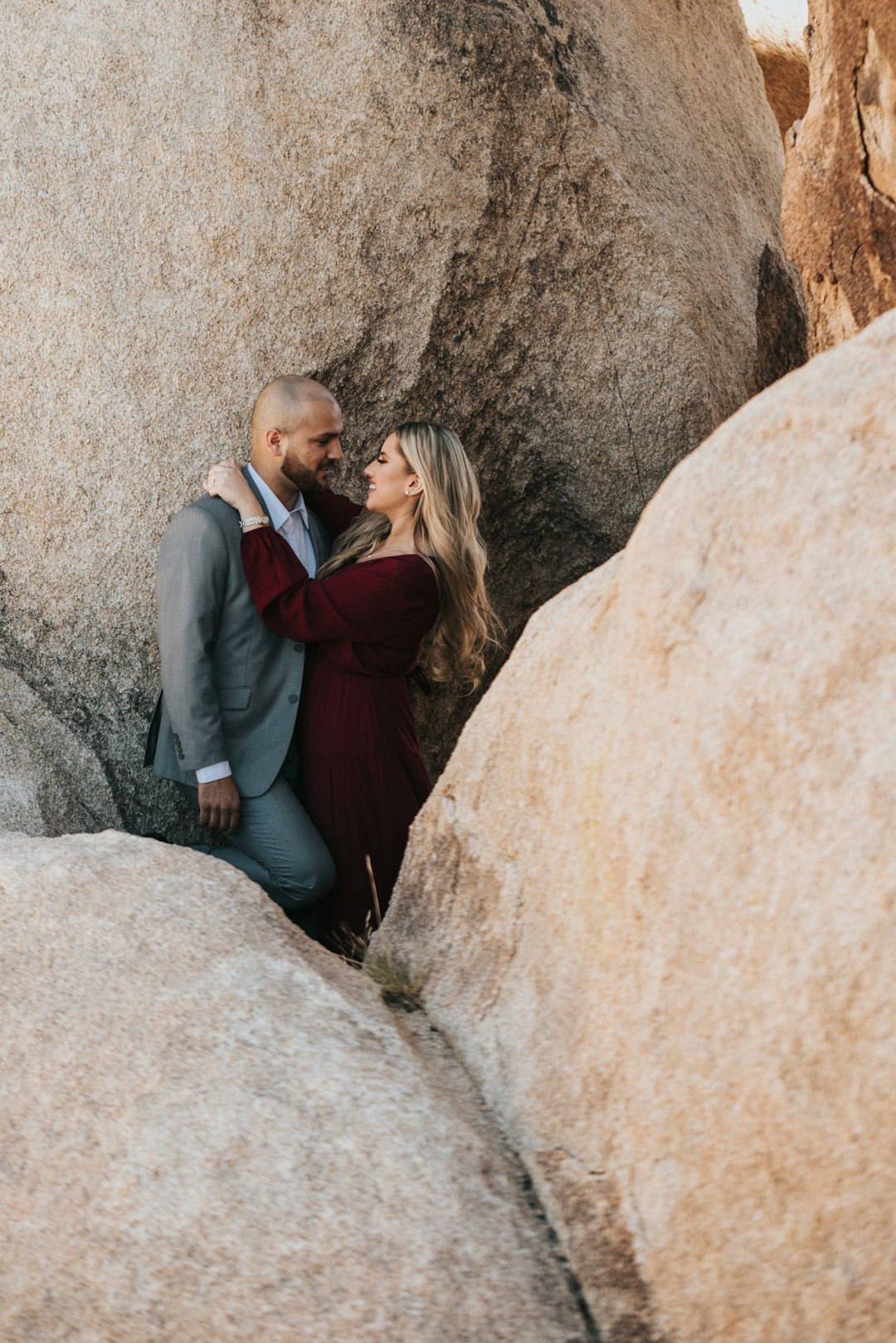 man and woman kissing beside brown rock