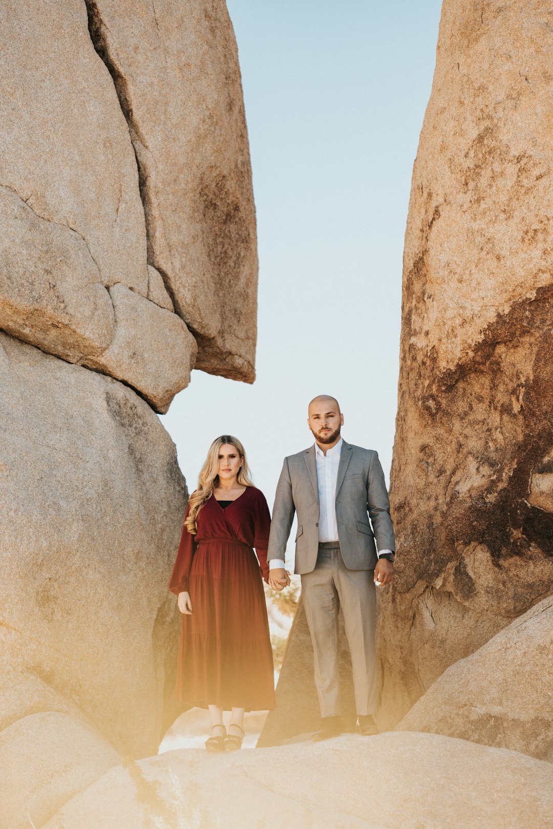 man and woman standing beside brown rock formation during daytime