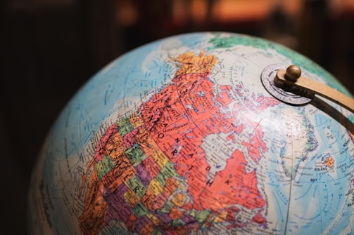 A globe is prominently featured, showcasing North America in detail. The geographic regions are marked in vibrant colors, with states and provinces clearly labeled. There's a metallic meridian ring with a pivot mechanism holding the globe.