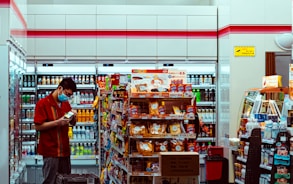 man in red t-shirt standing in front of food stall