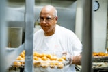 man in white crew neck t-shirt holding tray of orange fruits