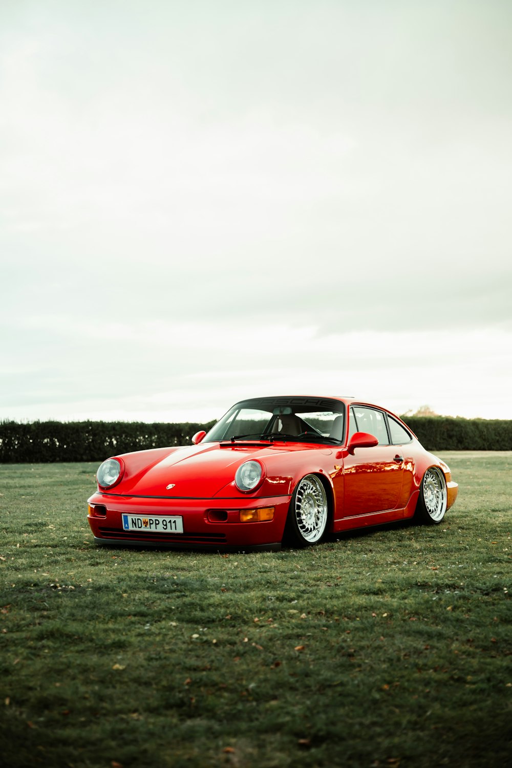 red porsche 911 on green grass field during daytime