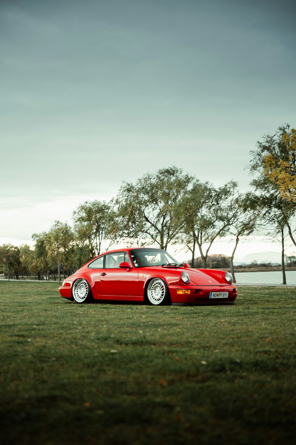 red porsche 911 on green grass field during daytime