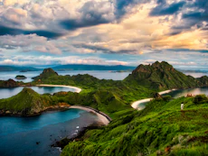 green and brown mountains near body of water under white clouds and blue sky during daytime