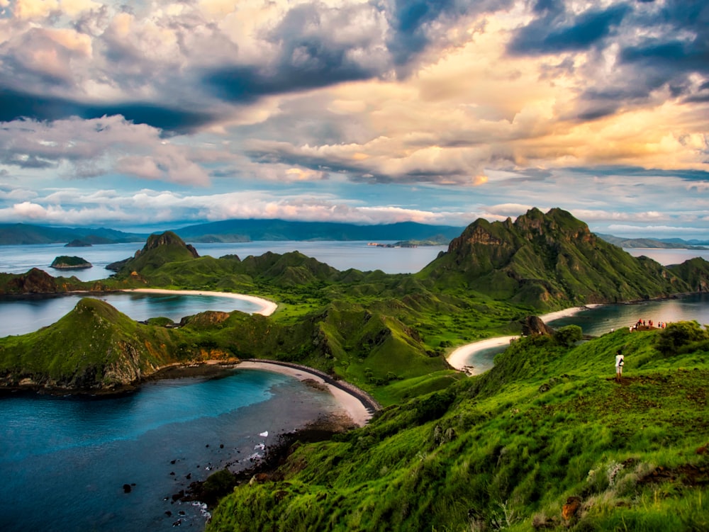 green and brown mountains near body of water under white clouds and blue sky during daytime