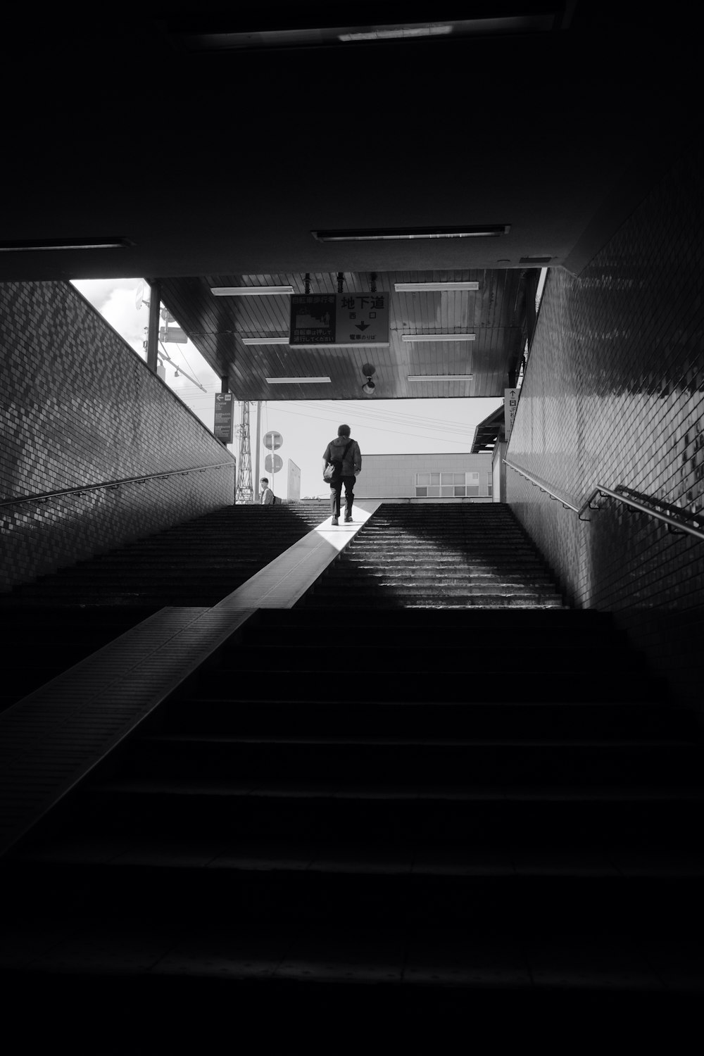 grayscale photo of woman walking on hallway