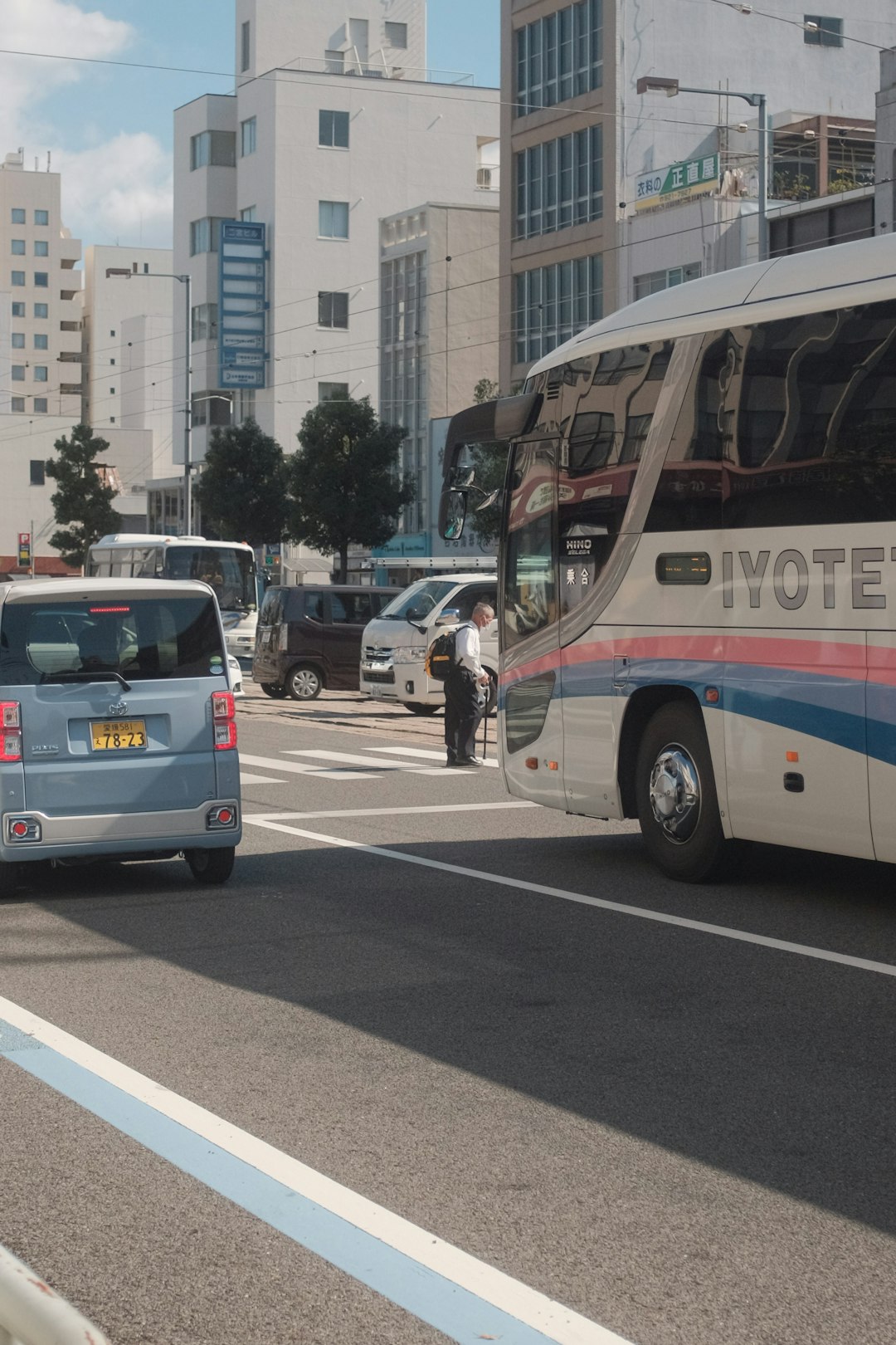 people walking on pedestrian lane near white and blue bus during daytime