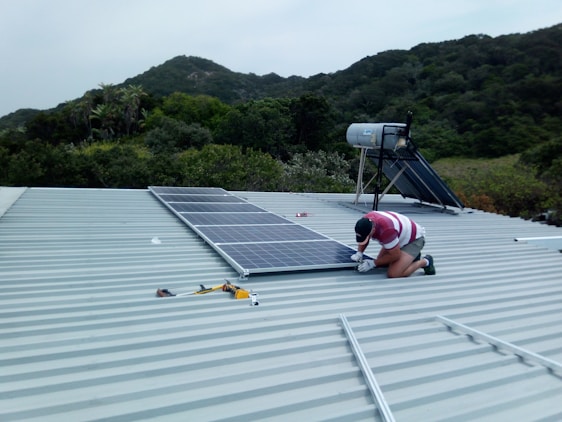 A friendly solar panel installer setting up photovoltaic panels on a sunny rooftop in Perpignan.
