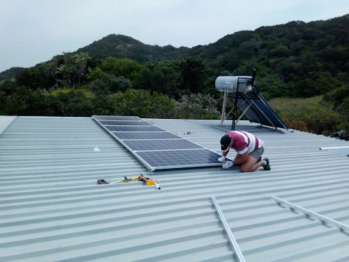 Technician installing solar panels in a rural village with a clear blue sky background