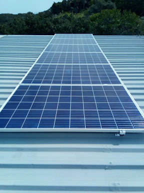 A rooftop solar panel installation gleaming under a clear blue sky.