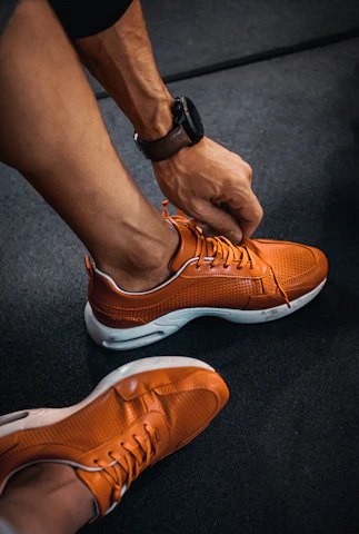 Close-up of hands tying running shoes with vibrant blue and orange colors in the background.
