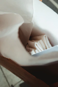 Hands inspecting a freshly printed paper bag in a bright, modern workspace with natural light.