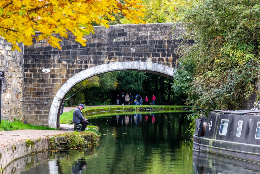 man in black jacket sitting on bench near river during daytime