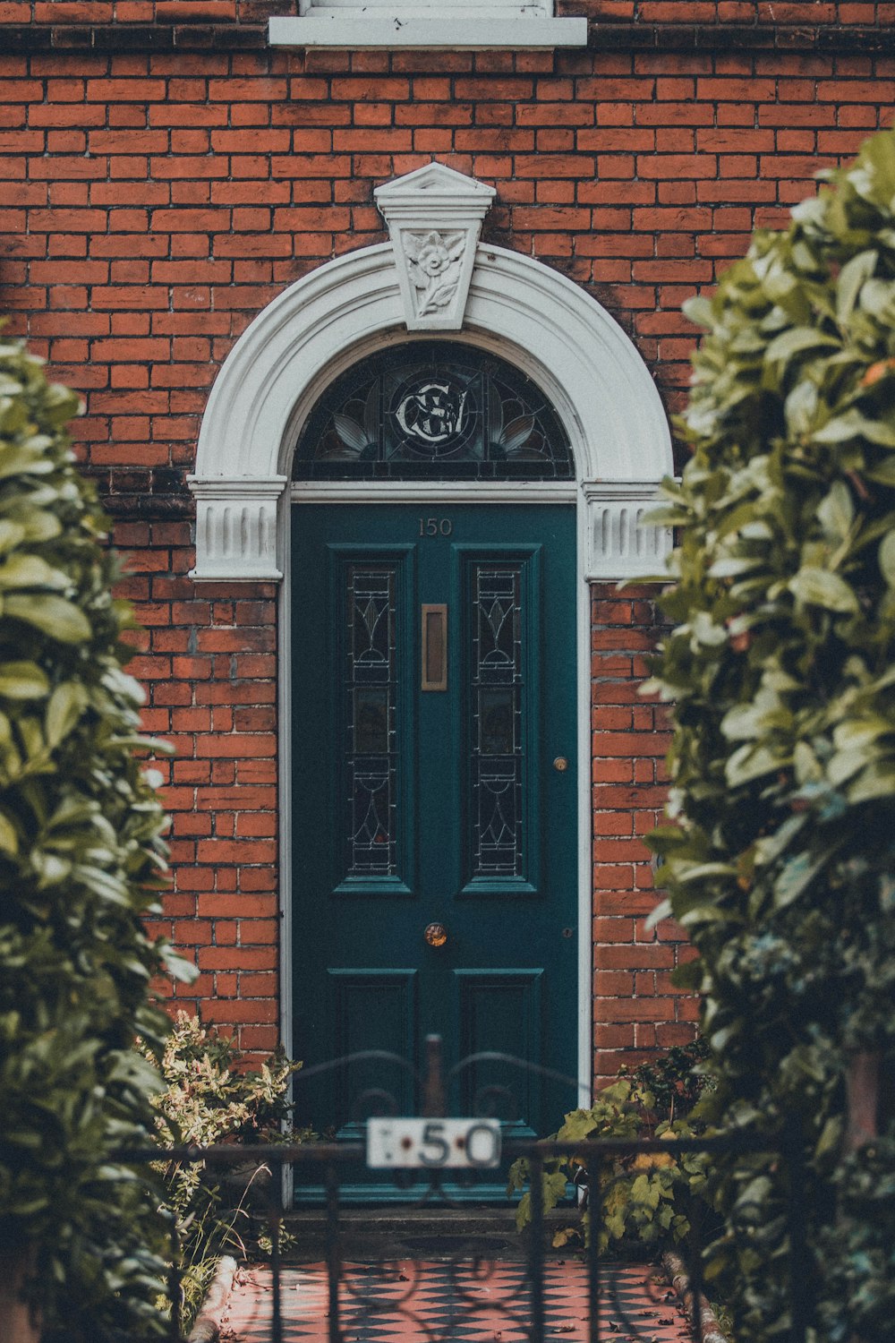 green wooden door on brown brick wall