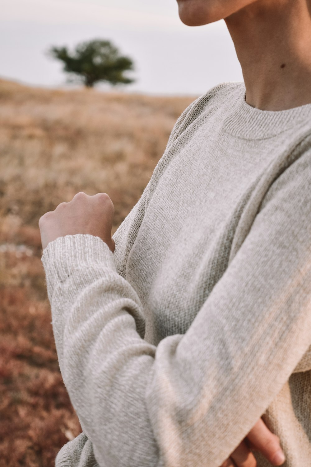 Uomo in maglione grigio in piedi sul campo marrone durante il giorno