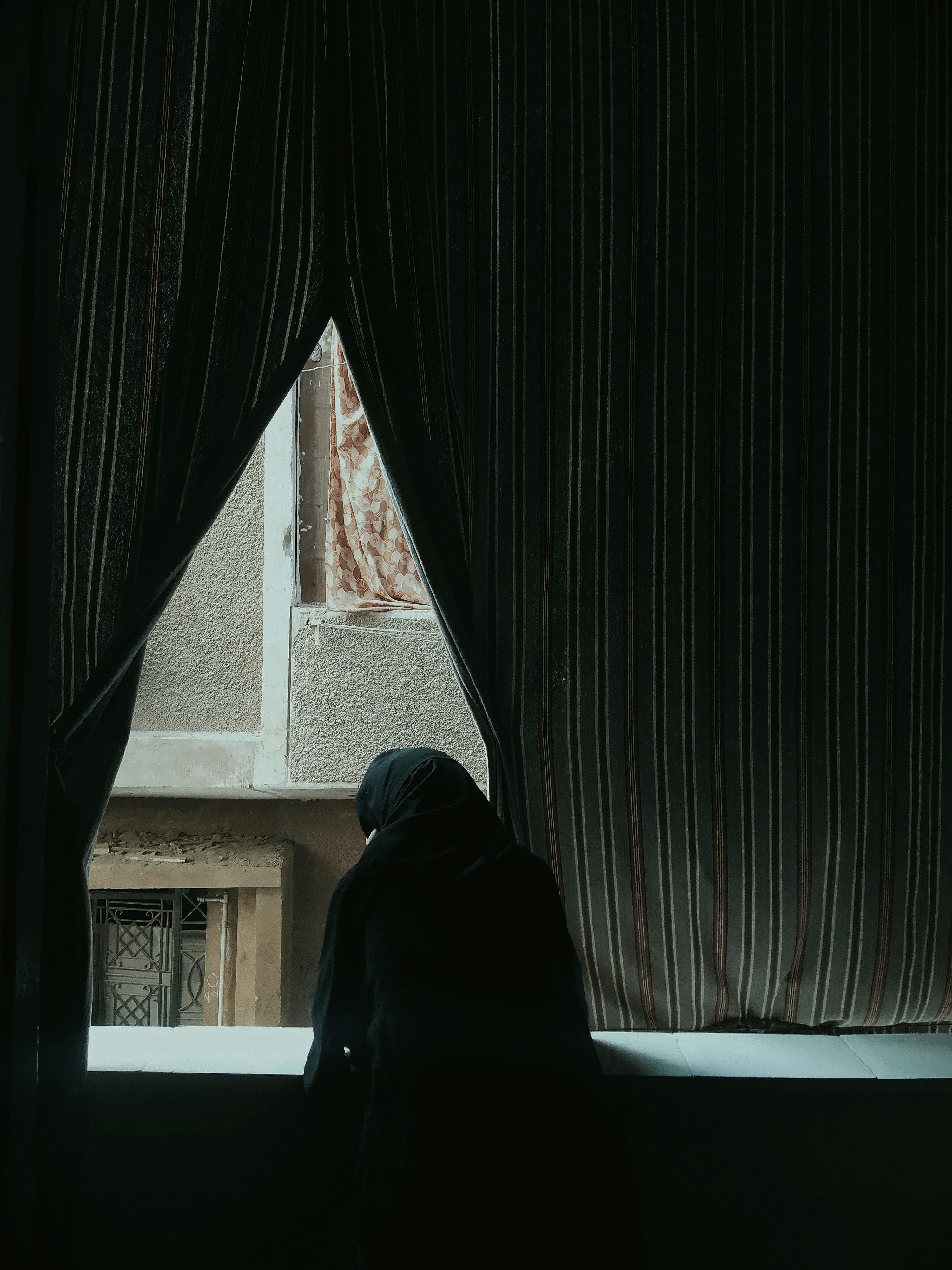 person in black hoodie sitting beside window