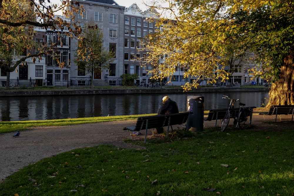 man and woman sitting on bench near body of water during daytime