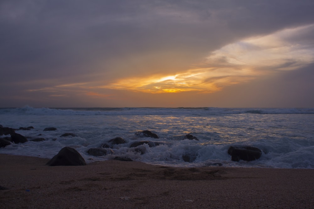 sea waves crashing on shore during sunset