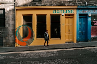 man in black jacket walking on sidewalk near brown wooden door during daytime