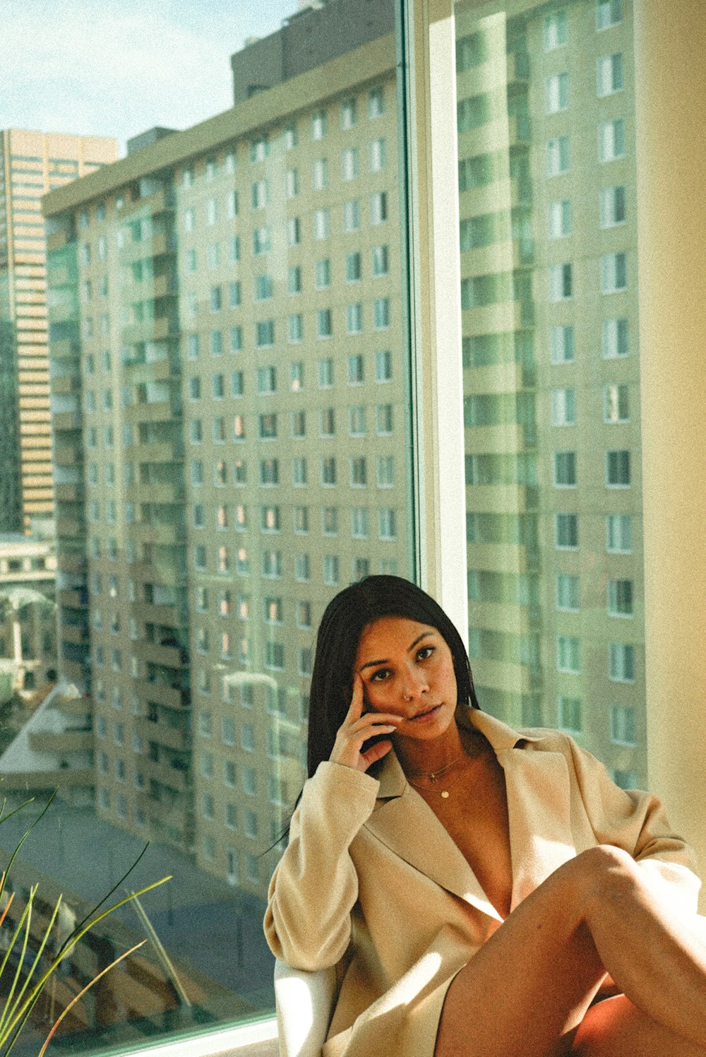 woman in beige coat standing near glass window