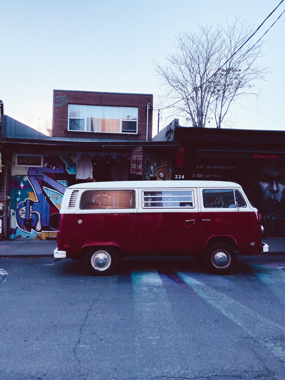 red and white volkswagen t-2 parked beside brown building during daytime