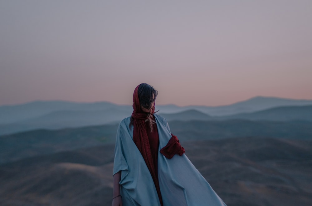 person in white robe standing on gray field during daytime