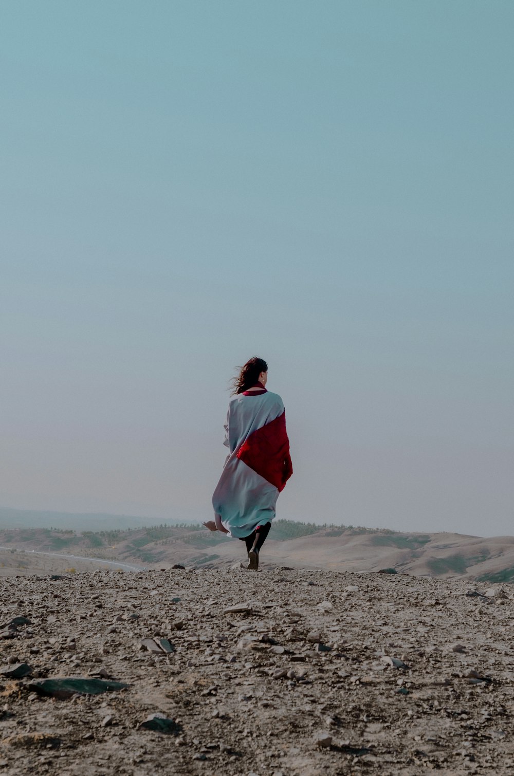 Frau in weiß-rotem Kleid tagsüber auf braunem Sand stehend