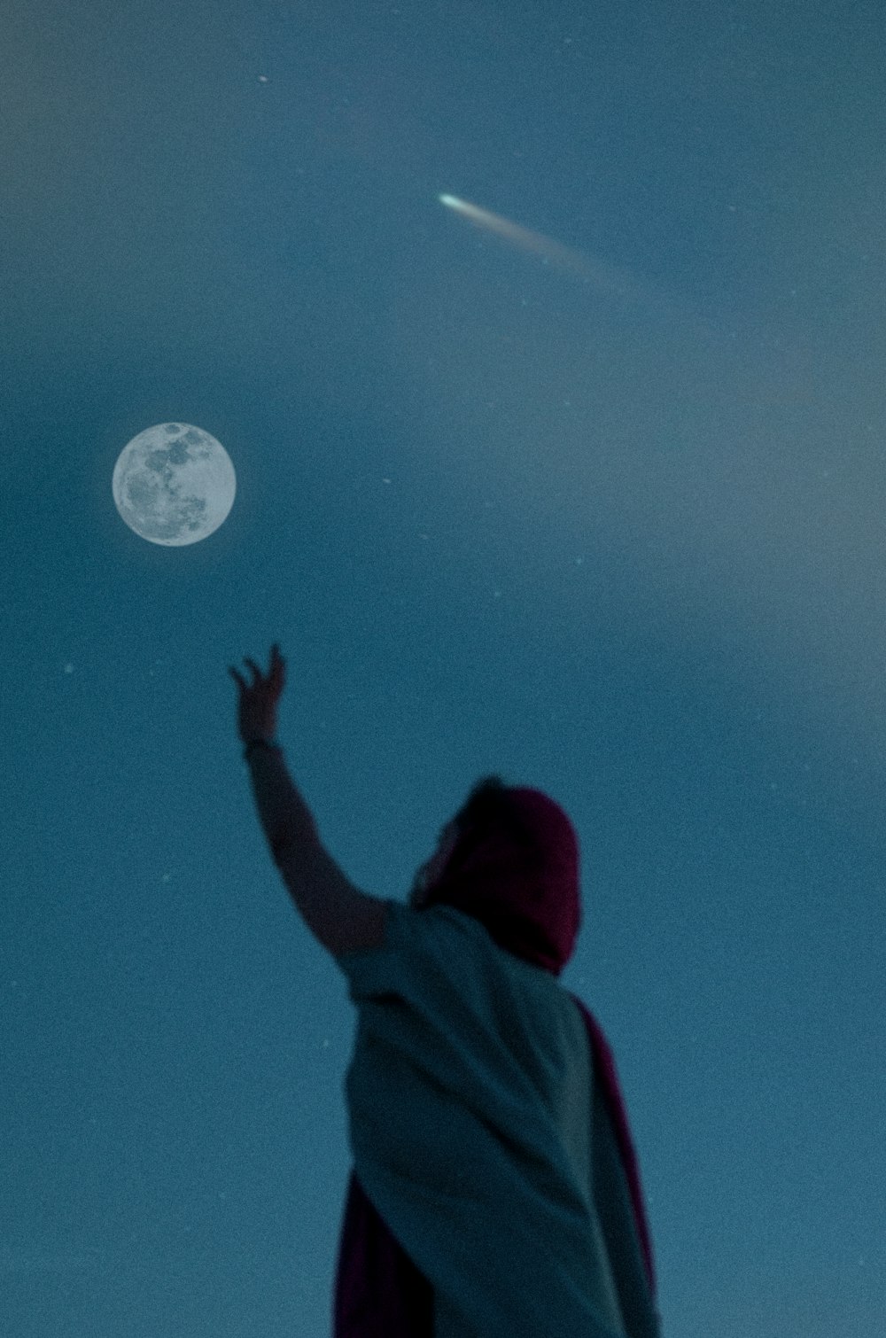 Persona con sudadera con capucha roja mirando a la luna