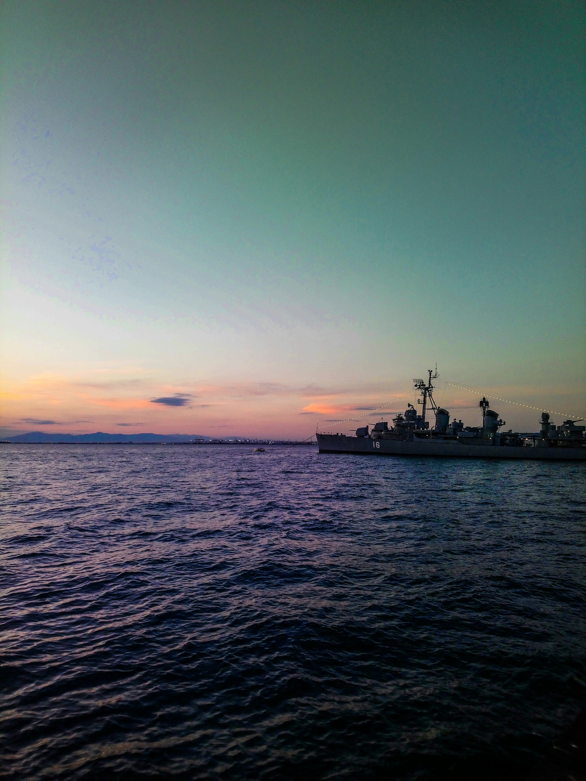 Close-up of a powerful warship cutting through ocean waves at sunset, evoking excitement and boldness.