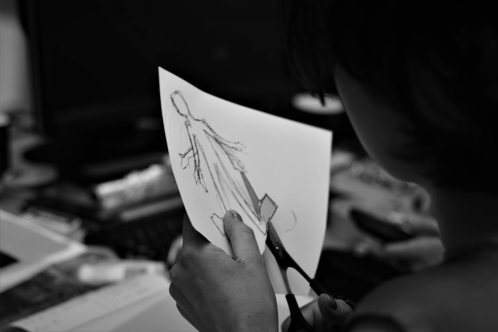 흰 종이에 펜을 들고 있는 여자의 회색조 사진